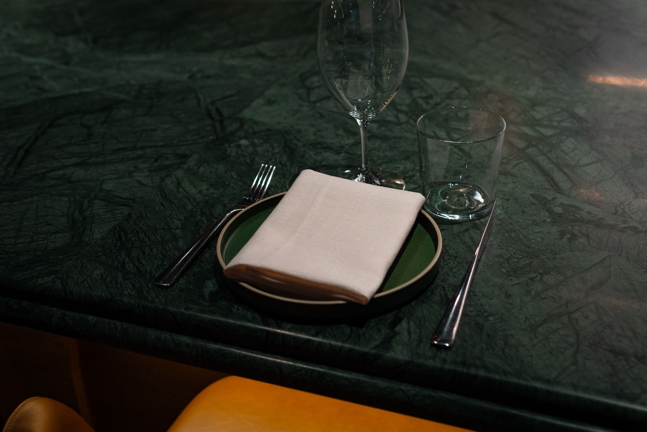 A stylish table setup featuring a napkin, fork, and glassware on a green marble countertop.